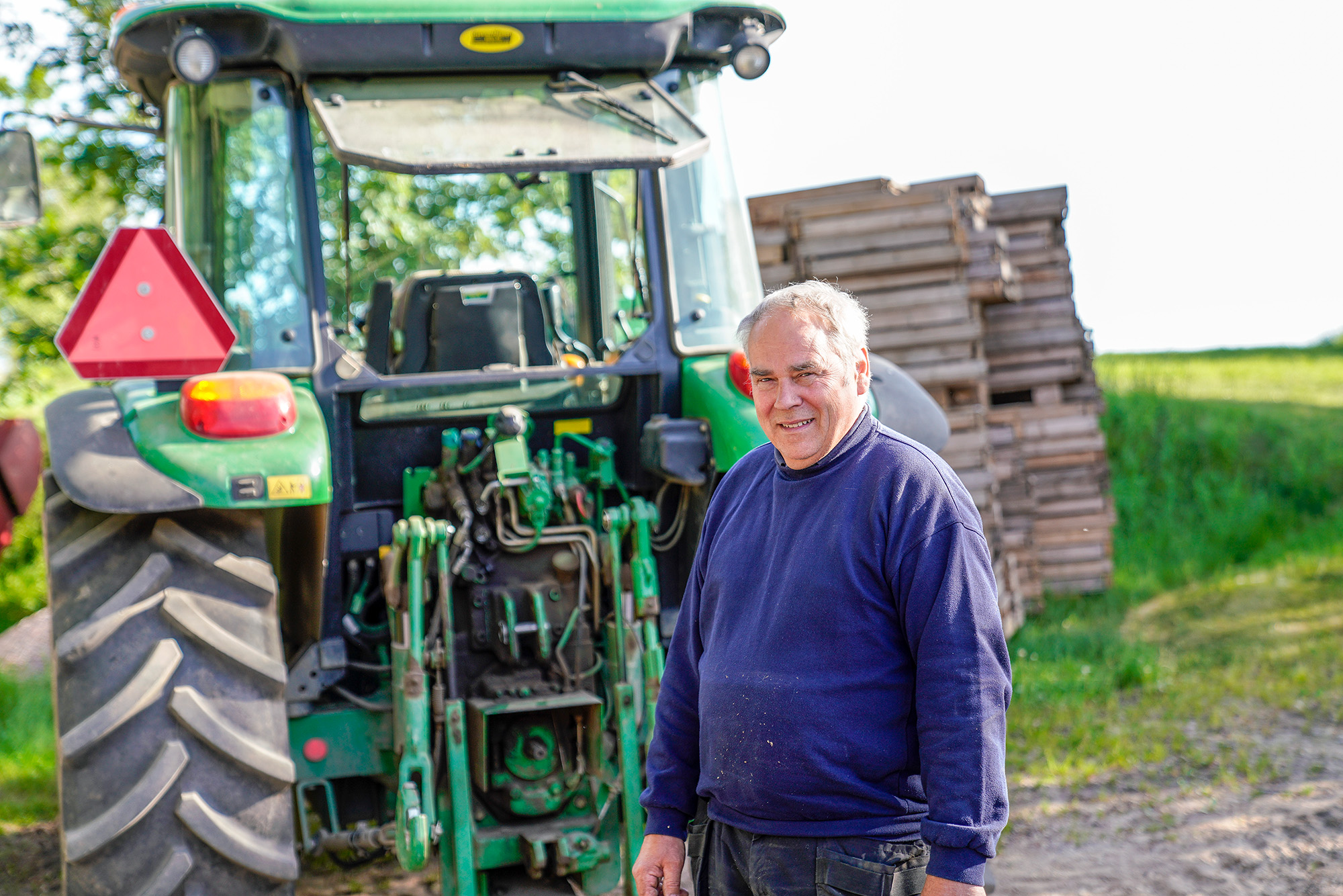 Anders Johansson står vid sin traktor på sin odling